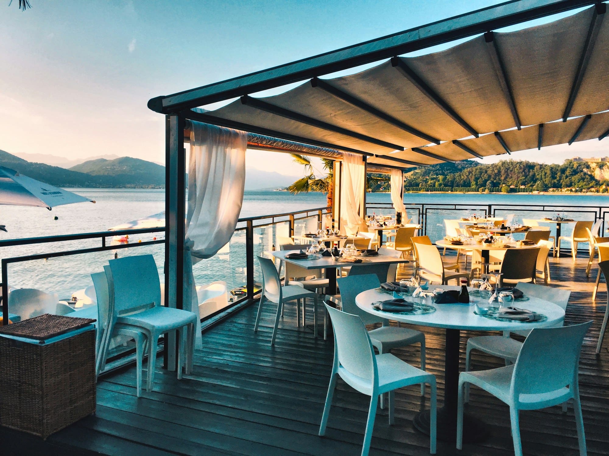 A seaside restaurant terrace set for dinner as evening falls