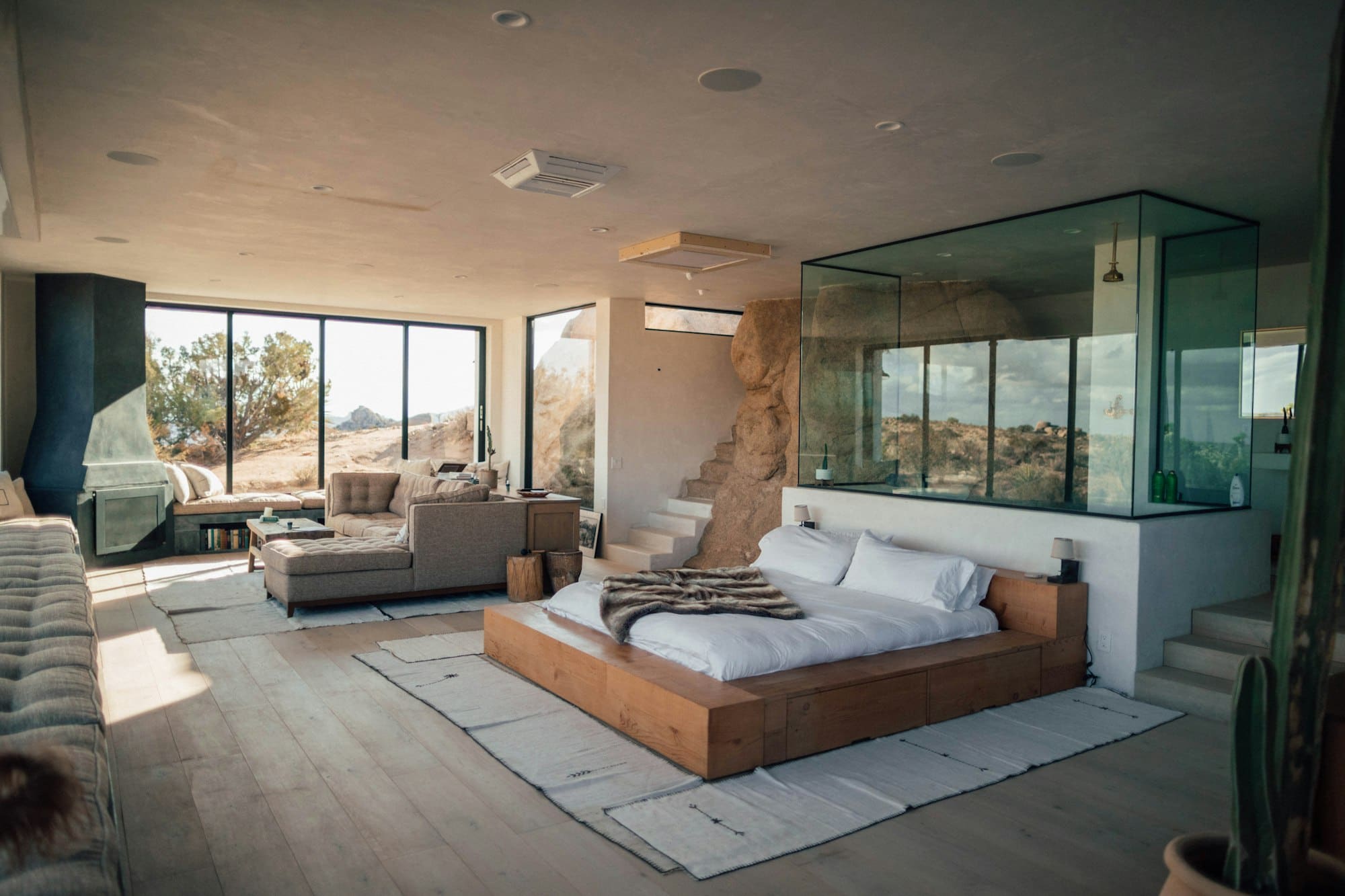 A contemporary suite with floor-to-ceiling windows and a glass-walled bathroom
